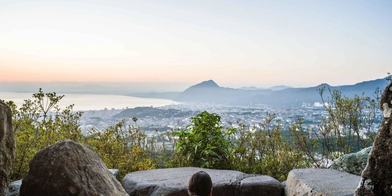 Stone-edged outdoor onsen overlooking Beppu city and its distant bay