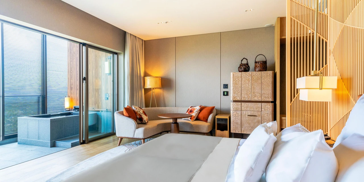 A Beppu guest room with warm timber, soft textiles and a window-side living area