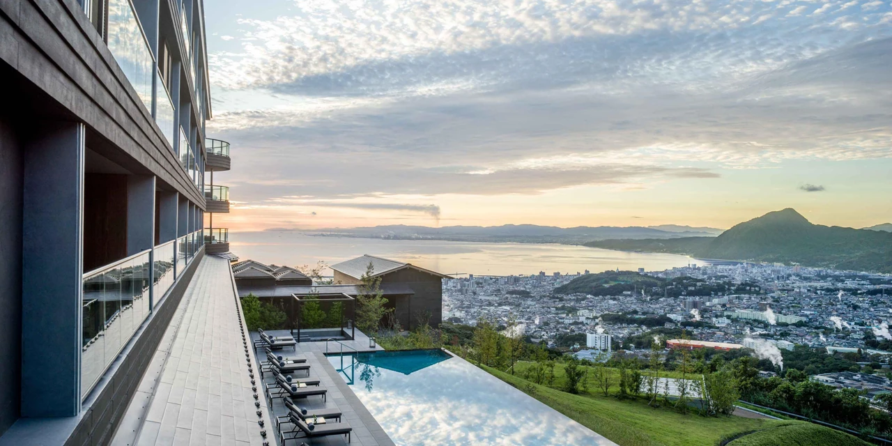 The terrace at ANA InterContinental Beppu overlooking the pool, city and bay in morning light