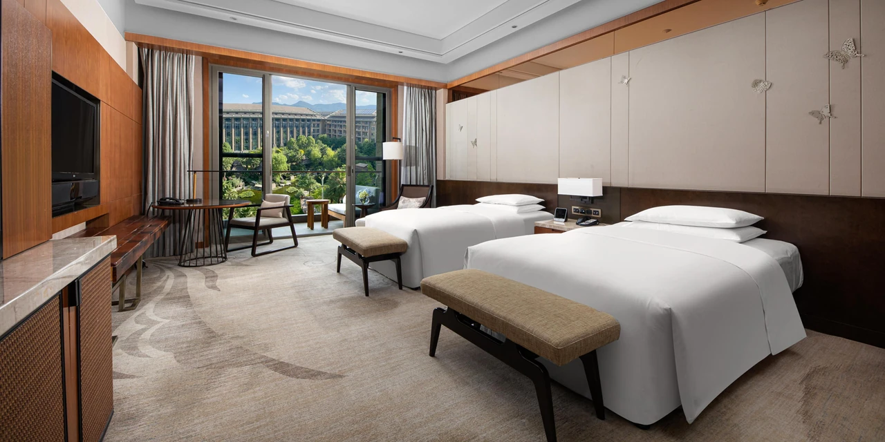 A twin room at InterContinental Kunming with window seating and greenery outside