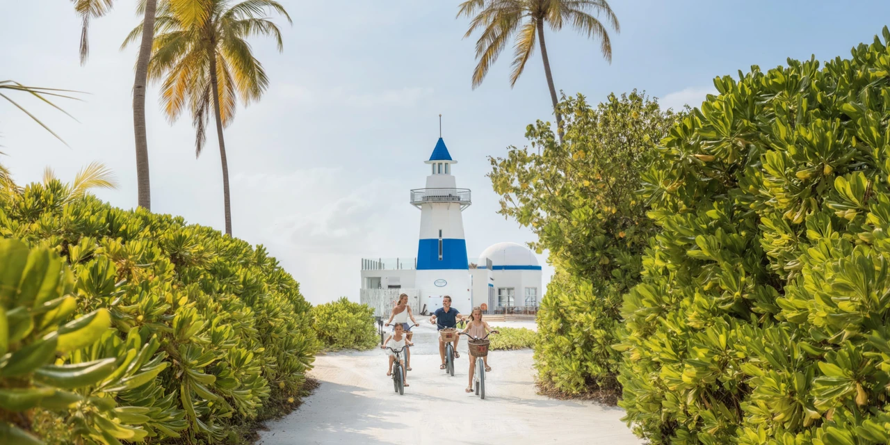 An island path beside the resort’s white lighthouse building with a blue roof