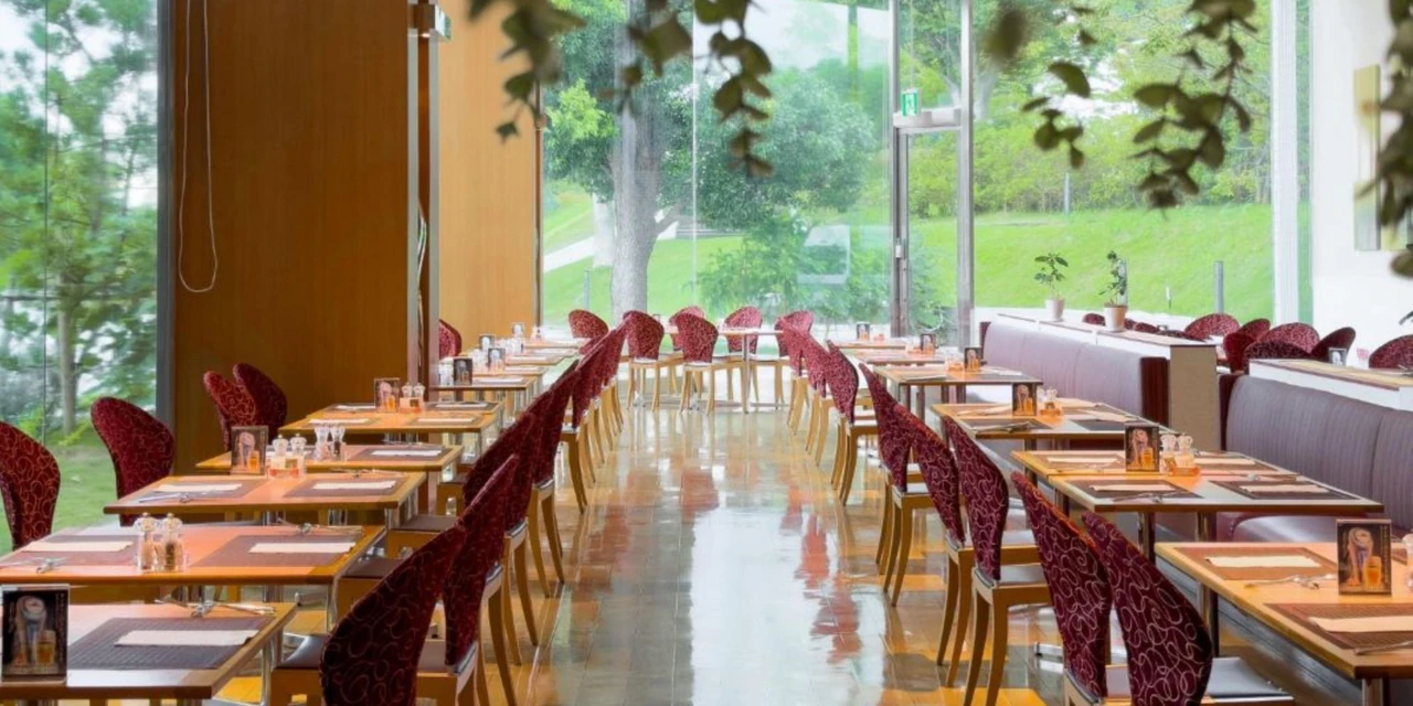Window-side restaurant tables, red chairs and greenery outside at ANA Crowne Plaza Narita