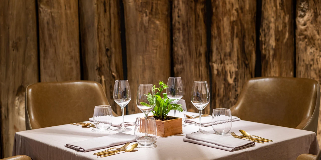 A Phuket resort restaurant with timber walls, a table for two and carefully arranged table settings