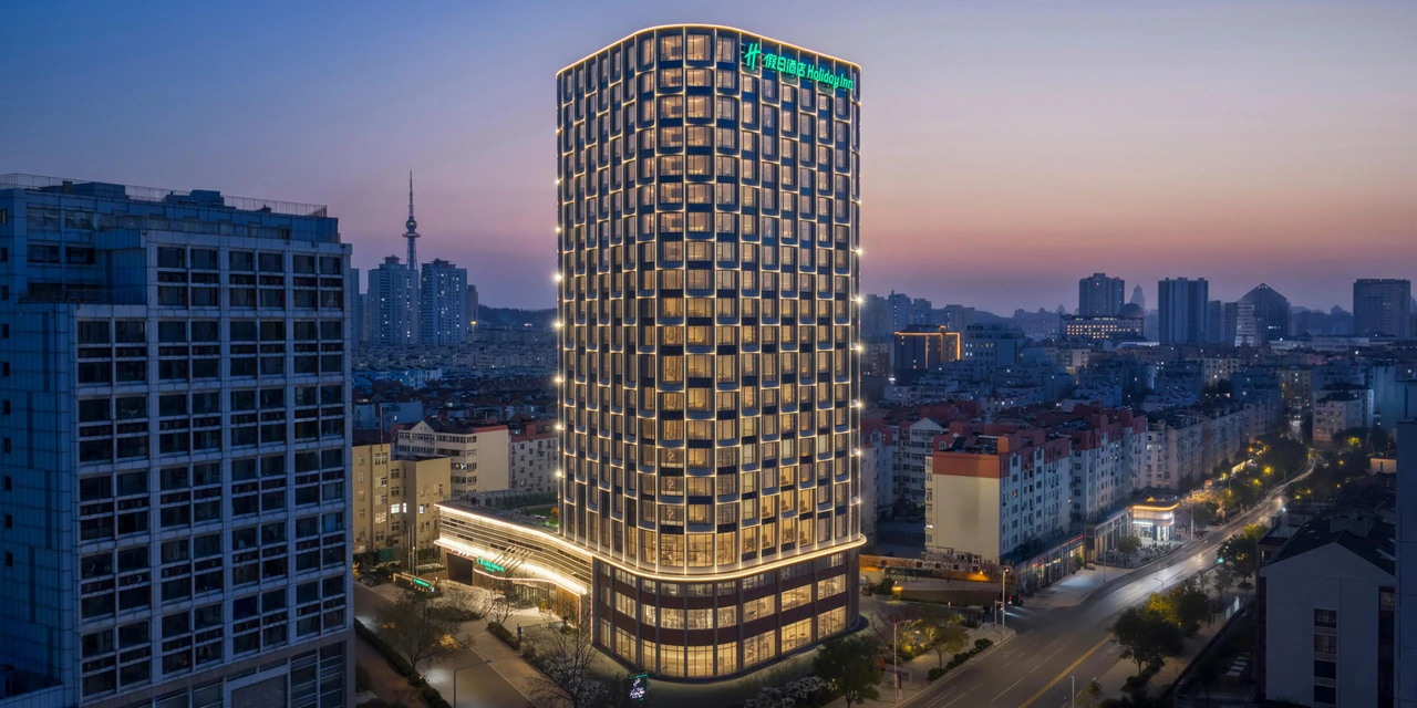 Holiday Inn Qingdao CBD’s tower, golden facade lighting and surrounding streets at dusk
