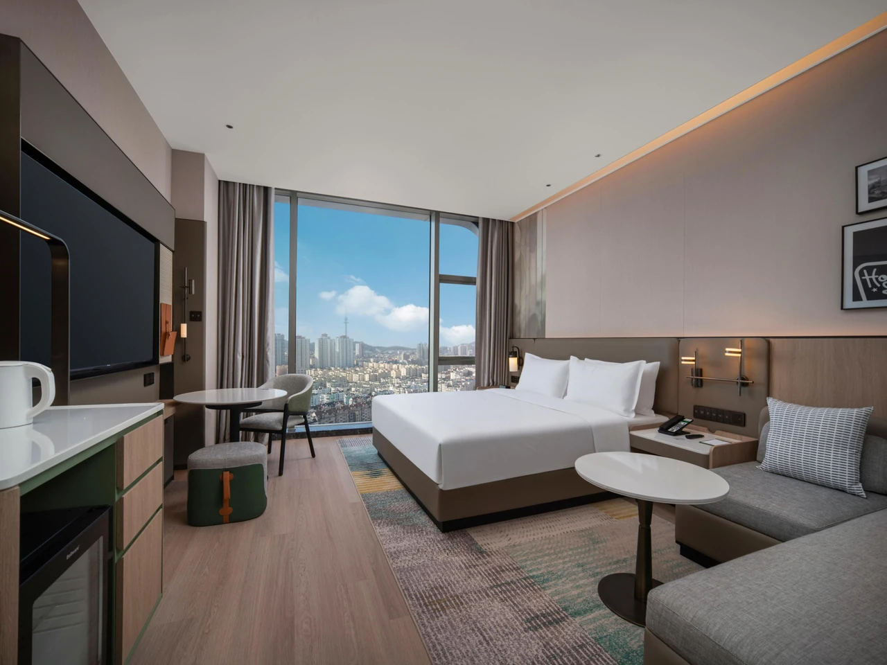 A king guest room, window-side seating and city views at Holiday Inn Qingdao CBD
