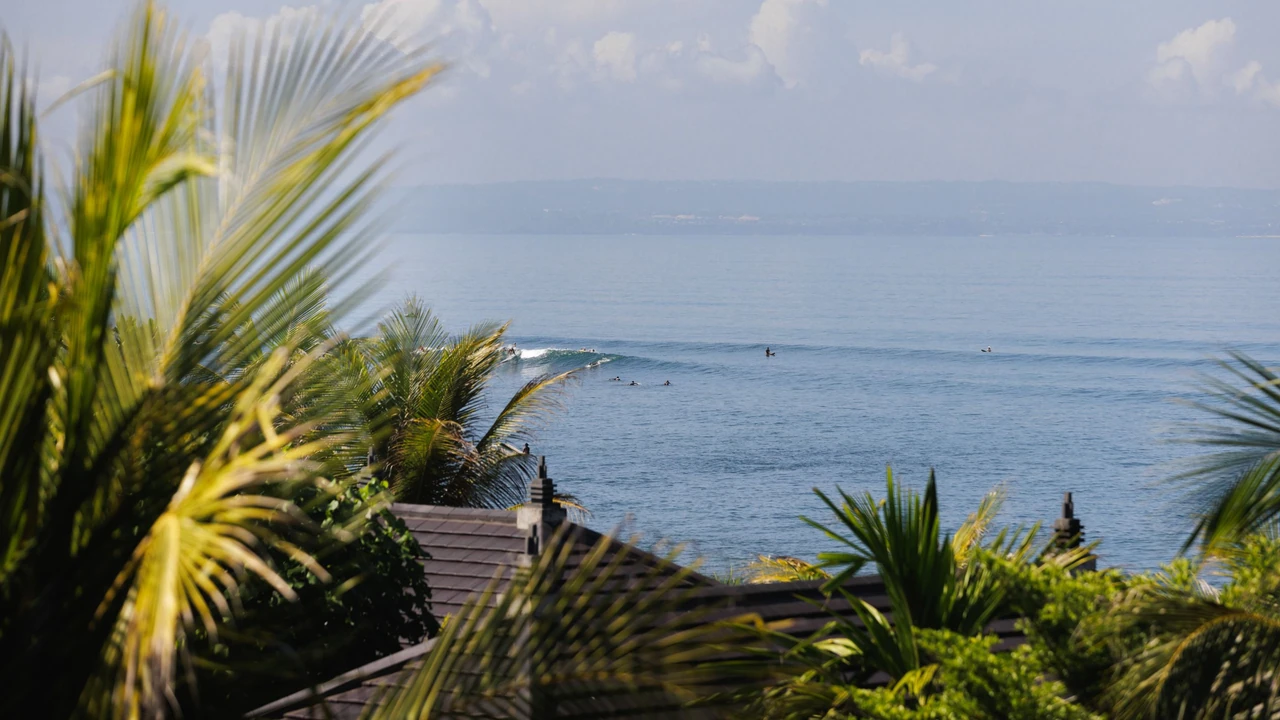 Ocean waves framed by palms and rooftops at Regent Bali Canggu