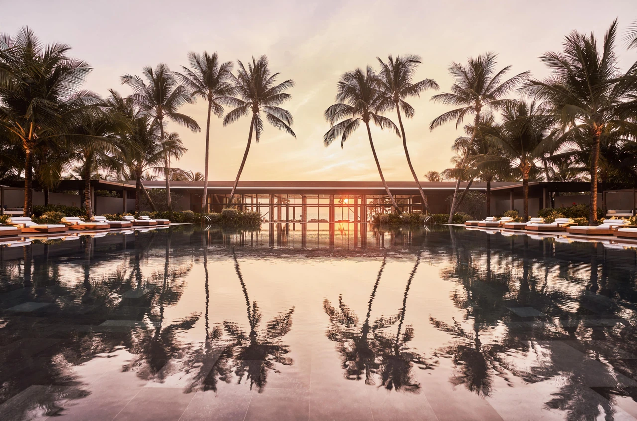 Palm trees and sunset reflected in Regent Phu Quoc’s main pool