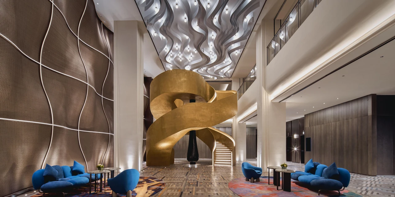 A golden spiral staircase, rippling ceiling and blue seating in Indigo Yantai’s lobby